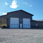 A charcoal post-frame agriculture storage building with wainscoting and overhead doors