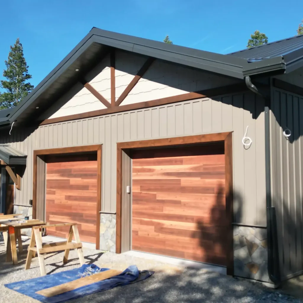 A custom residential post-frame home with soffits, and overhead doors