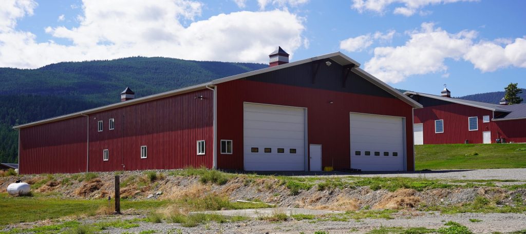 A dark red post-frame agriculture storage building with cupolas