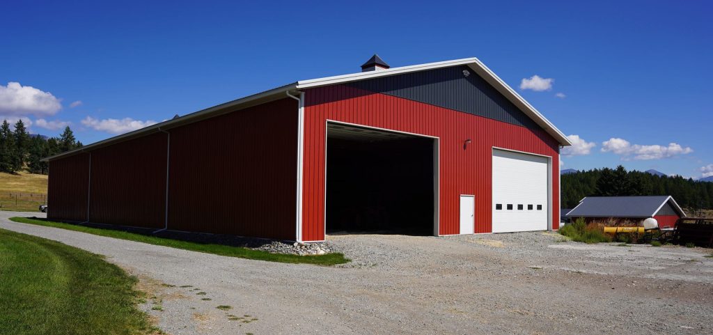 A dark red post-frame agriculture storage building with cupolas