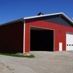 A dark red post-frame agriculture storage building with cupolas