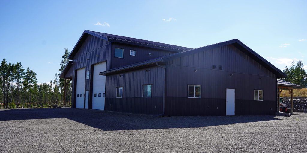 A charcoal post-frame agriculture storage building with wainscoting and overhead doors