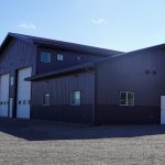 A charcoal post-frame agriculture storage building with wainscoting and overhead doors