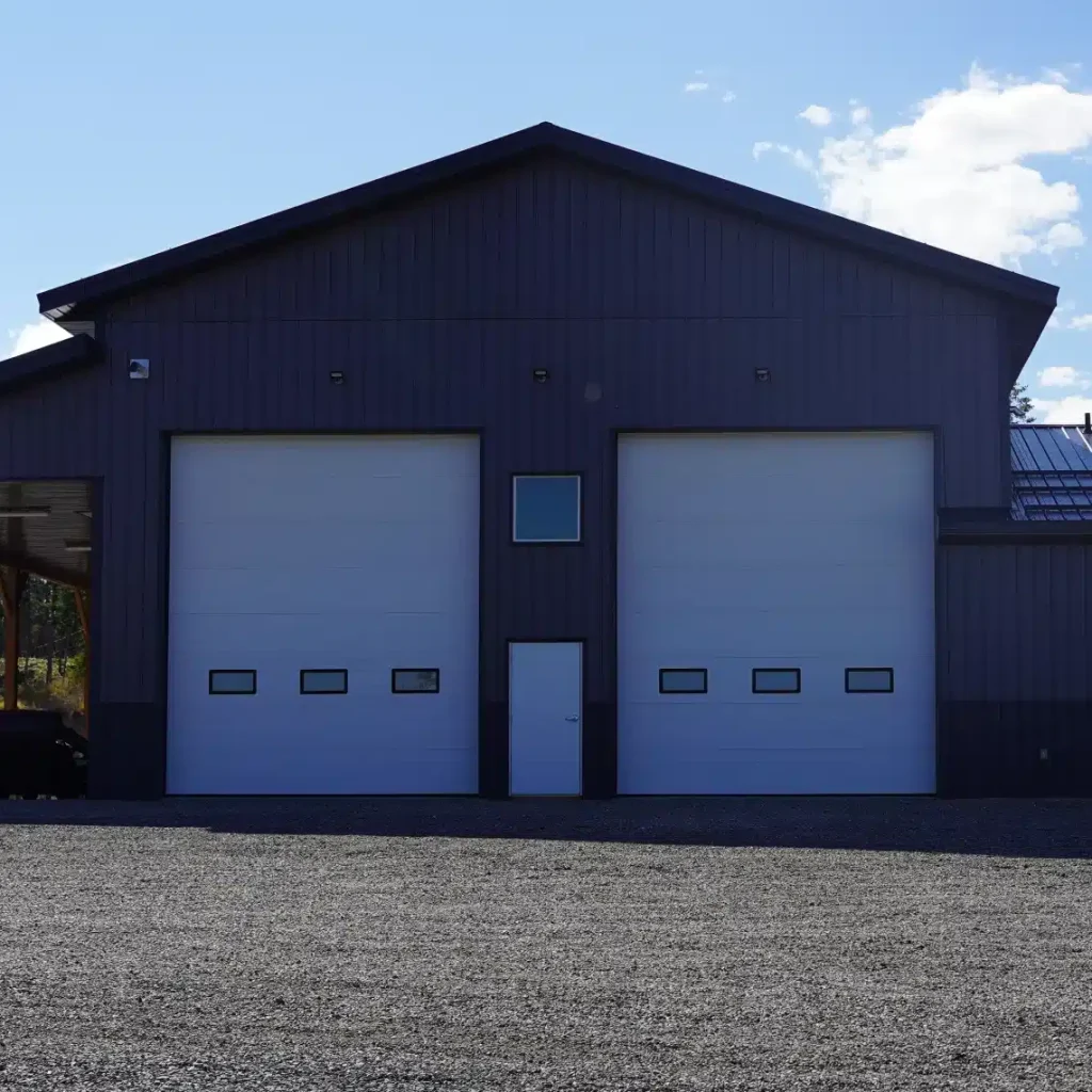 A charcoal post-frame agriculture storage building with wainscoting and overhead doors