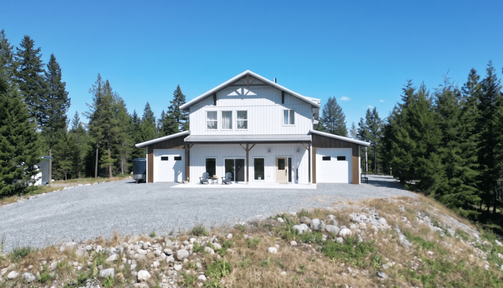 A custom white white post-frame Barndominium with timber accents, and a front porch