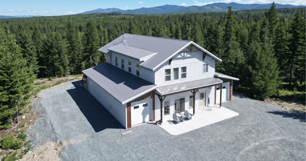 A custom white white post-frame Barndominium with timber accents, and a front porch