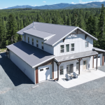 A custom white white post-frame Barndominium with timber accents, and a front porch