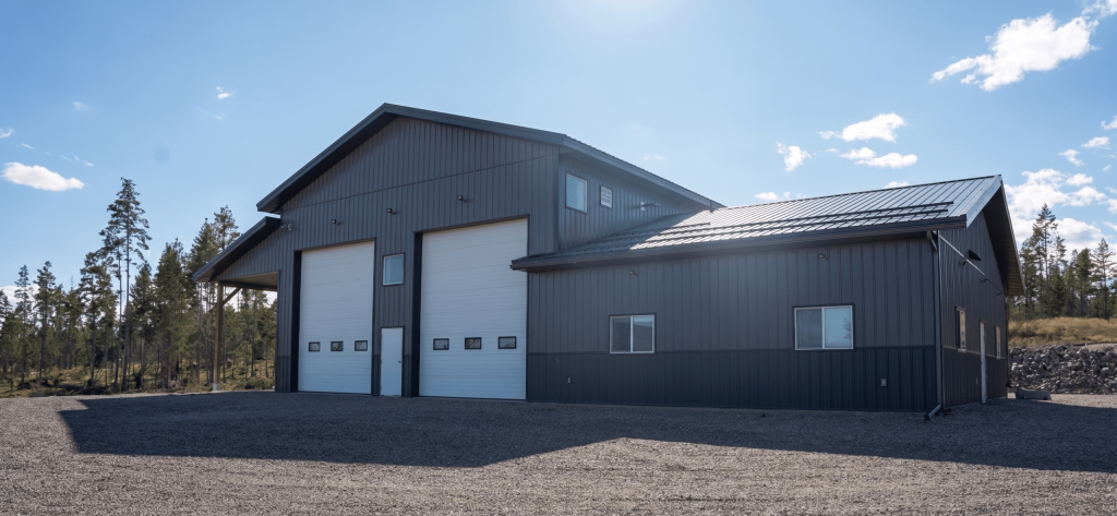 A charcoal post-frame agriculture storage building with wainscoting and overhead doors