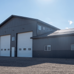 A charcoal post-frame agriculture storage building with wainscoting and overhead doors