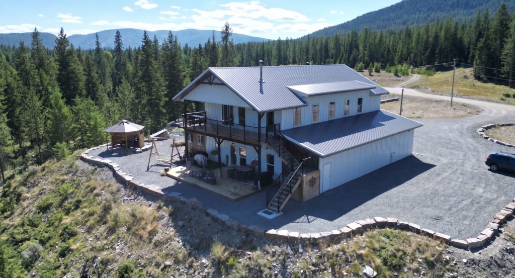 A custom white white post-frame Barndominium with timber accents, and a front porch