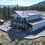 A custom white white post-frame Barndominium with timber accents, and a front porch