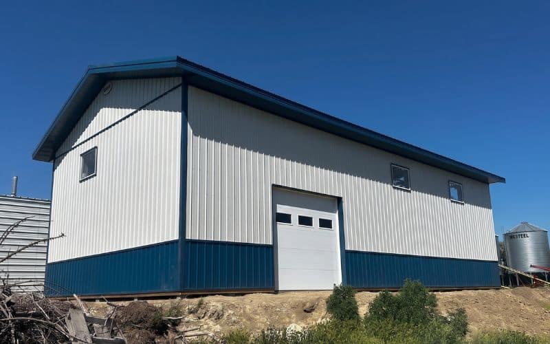 A white white post-frame agricultural shop with heron blue wainscoting
