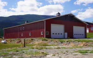 A dark red post-frame agriculture storage building with cupolas