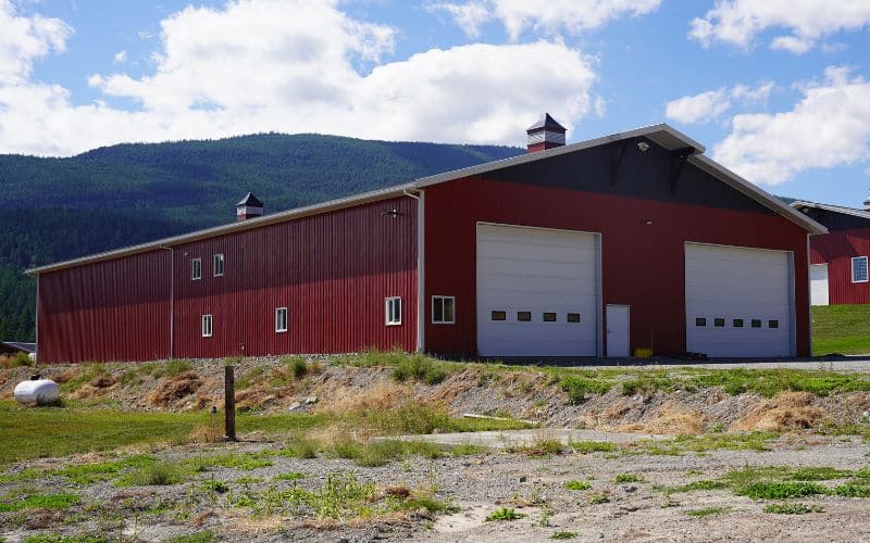 A dark red post-frame agriculture storage building with cupolas