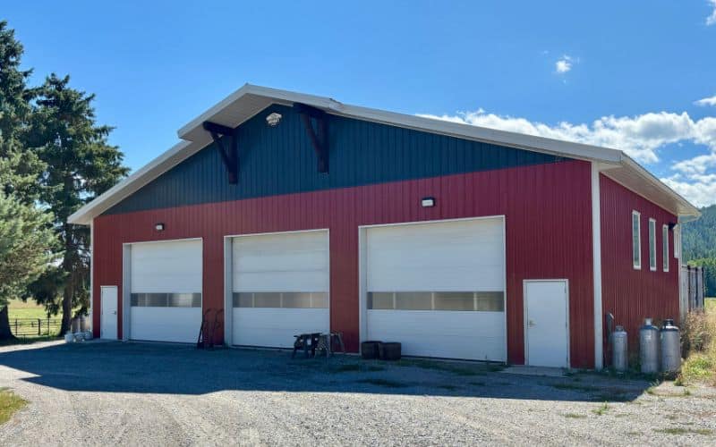 A Tile red post-frame stroage shop built with multiple overhead doors and crows peak