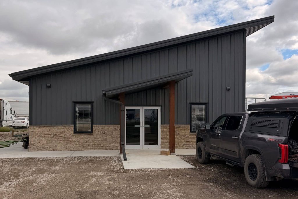 A charcoal post-frame commercial office building with wainscoting and a covered front entry way