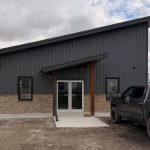 A charcoal post-frame commercial office building with wainscoting and a covered front entry way