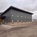 A charcoal post-frame commercial office building with wainscoting and a covered front entry way