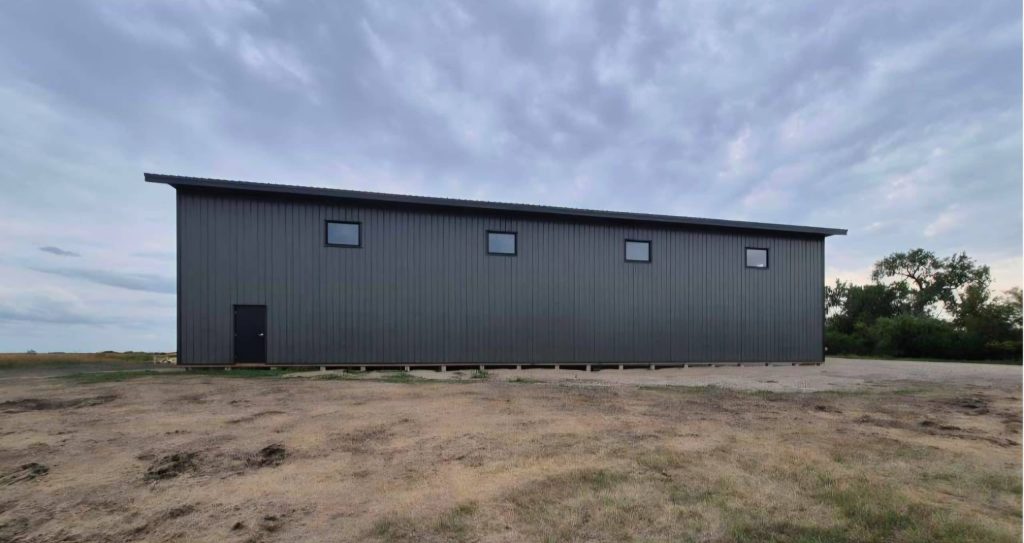 A dark sage post-frame agriculture machine shed