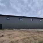 A dark sage post-frame agriculture machine shed