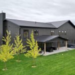 A post-frame custom home with a front porch, timber accents, and an attached garage