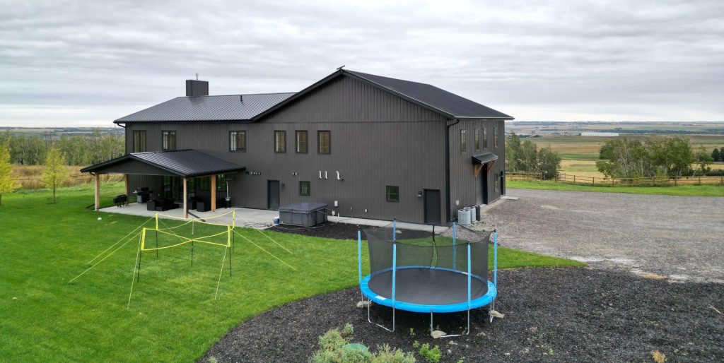 A post-frame custom home with a front porch, timber accents, and an attached garage