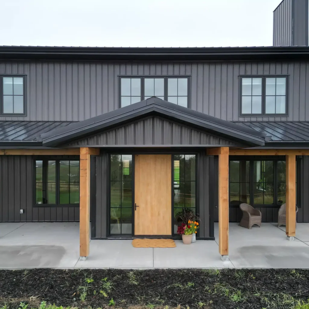 A post-frame custom home with a front porch, timber accents, and an attached garage