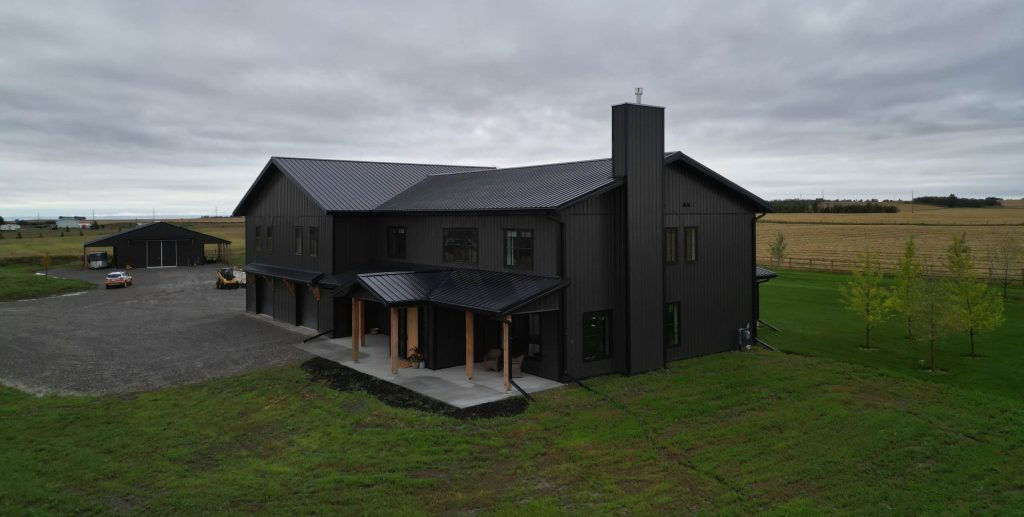 A post-frame custom home with a front porch, timber accents, and an attached garage