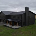 A post-frame custom home with a front porch, timber accents, and an attached garage