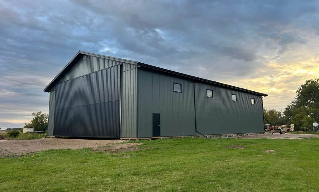 A dark sage post-frame agriculture machine shed