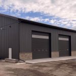 A charcoal post-frame commercial storage building with wainscoting and overhead doors