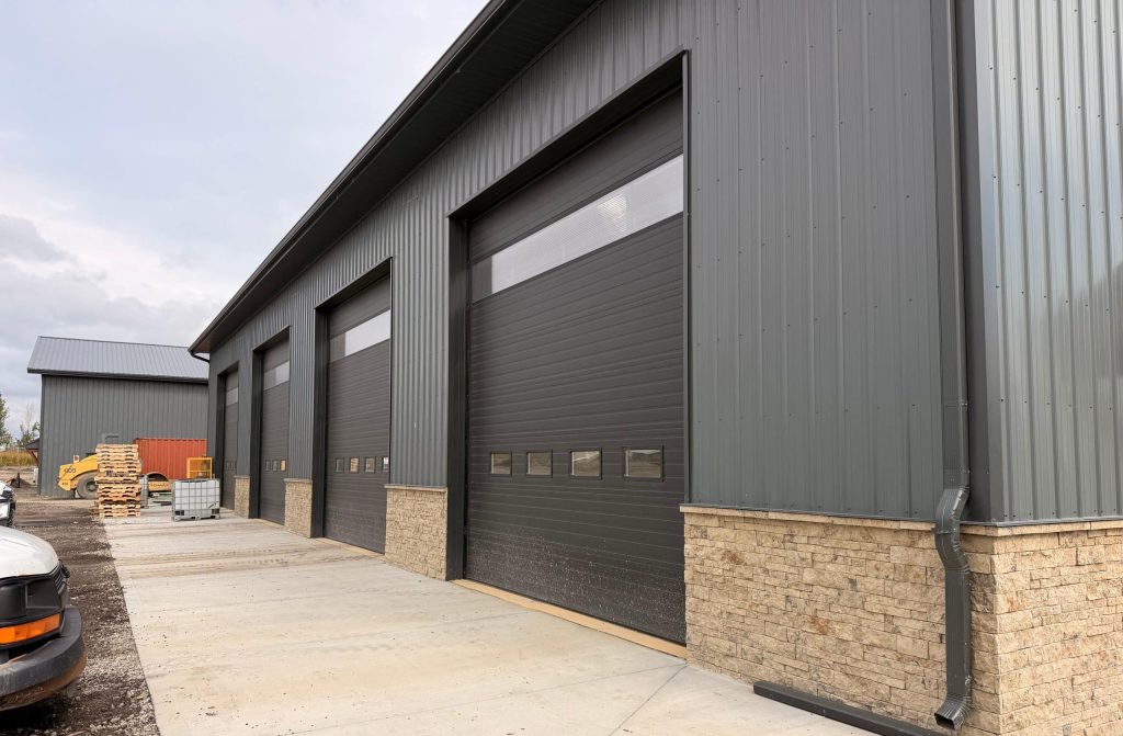 A charcoal post-frame commercial storage building with wainscoting and overhead doors