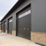 A charcoal post-frame commercial storage building with wainscoting and overhead doors
