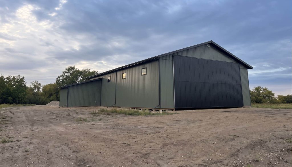 A dark sage post-frame agriculture machine shed