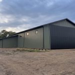 A dark sage post-frame agriculture machine shed