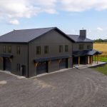 A post-frame custom home with a front porch, timber accents, and an attached garage