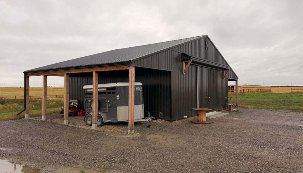 A post-frame storage barn with two open lean-tos and a sliding door