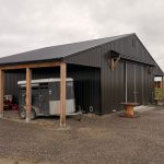 A post-frame storage barn with two open lean-tos and a sliding door