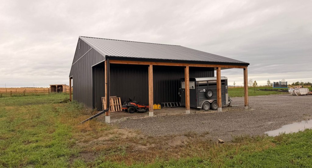 A post-frame storage barn with two open lean-tos and a sliding door