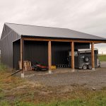 A post-frame storage barn with two open lean-tos and a sliding door