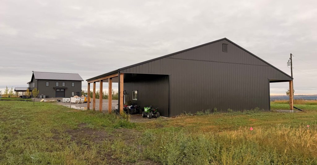 A post-frame storage barn with two open lean-tos and a sliding door