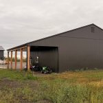 A post-frame storage barn with two open lean-tos and a sliding door