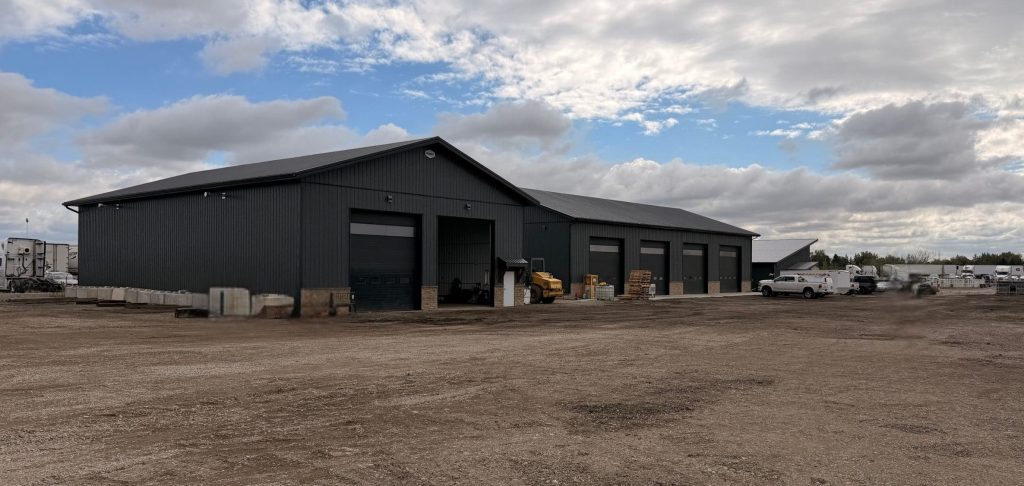 A charcoal post-frame commercial storage building with wainscoting and overhead doors