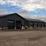 A charcoal post-frame commercial storage building with wainscoting and overhead doors
