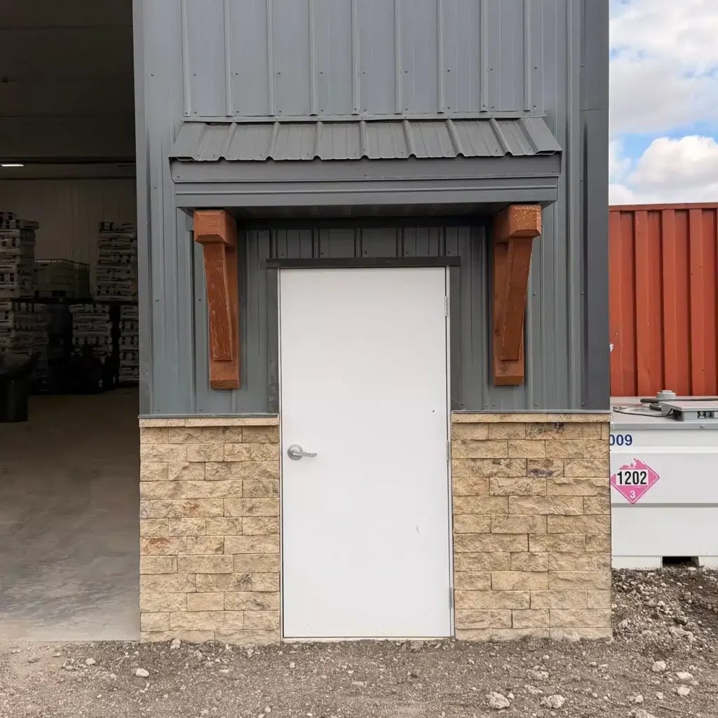 A gunmetal post-frame storage building with wainscoting, soffits, and overhead doors