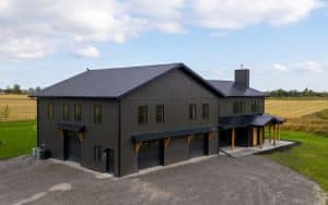 A post-frame custom home with a front porch, timber accents, and an attached garage