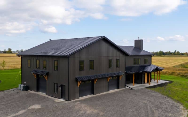 A post-frame custom home with a front porch, timber accents, and an attached garage