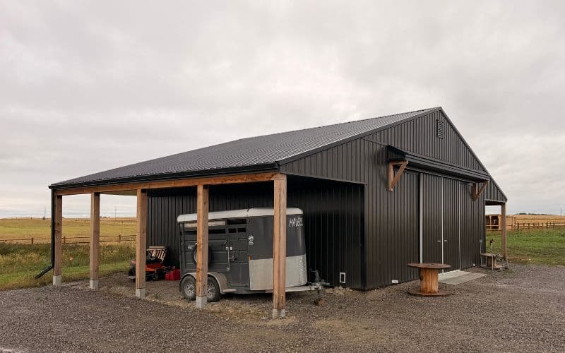 A post-frame storage barn with two open lean-tos and a sliding door