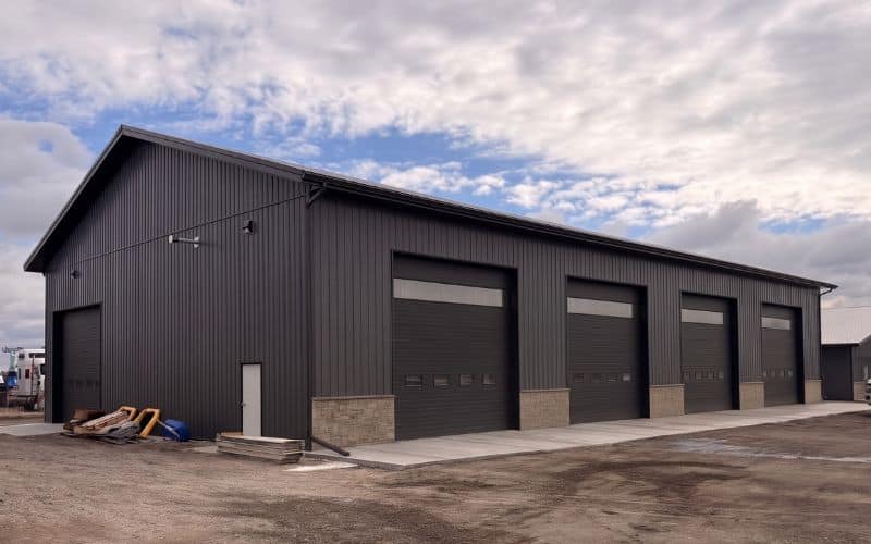 A charcoal post-frame commercial storage building with wainscoting and overhead doors