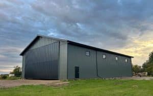 A dark sage post-frame agriculture machine shed